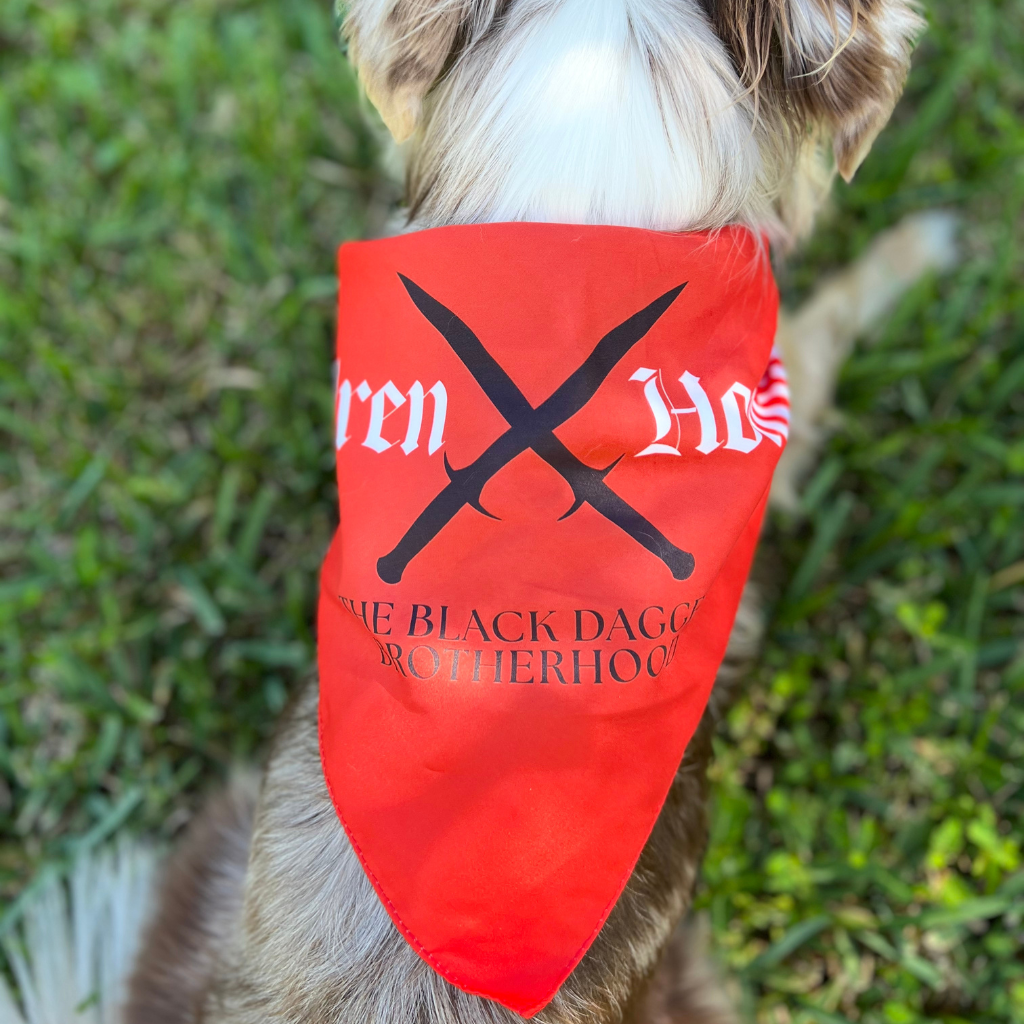 Dog wearing a red bandana with text and logo on grass