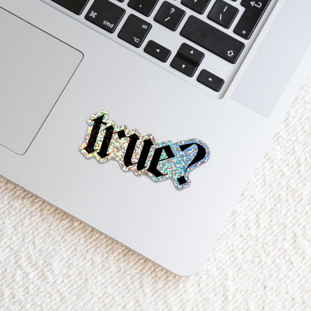 Holographic sticker with 'true?' text on a laptop
