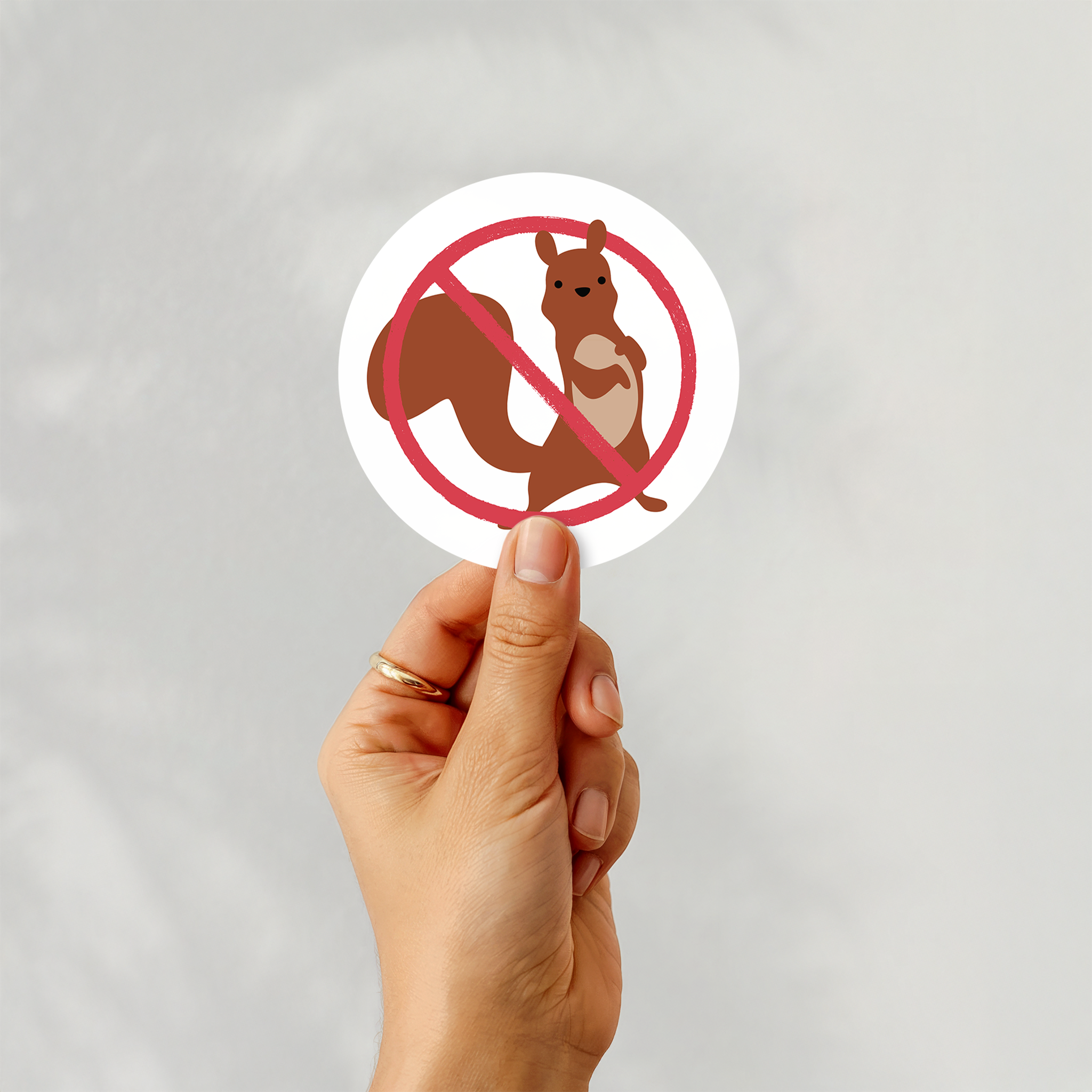 a woman holds a "no squirrels" sticker in her hand
