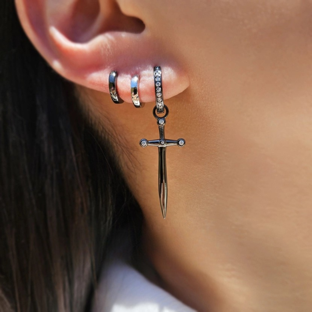 close up of a woman's ear wearing a tall dagger hoop earring