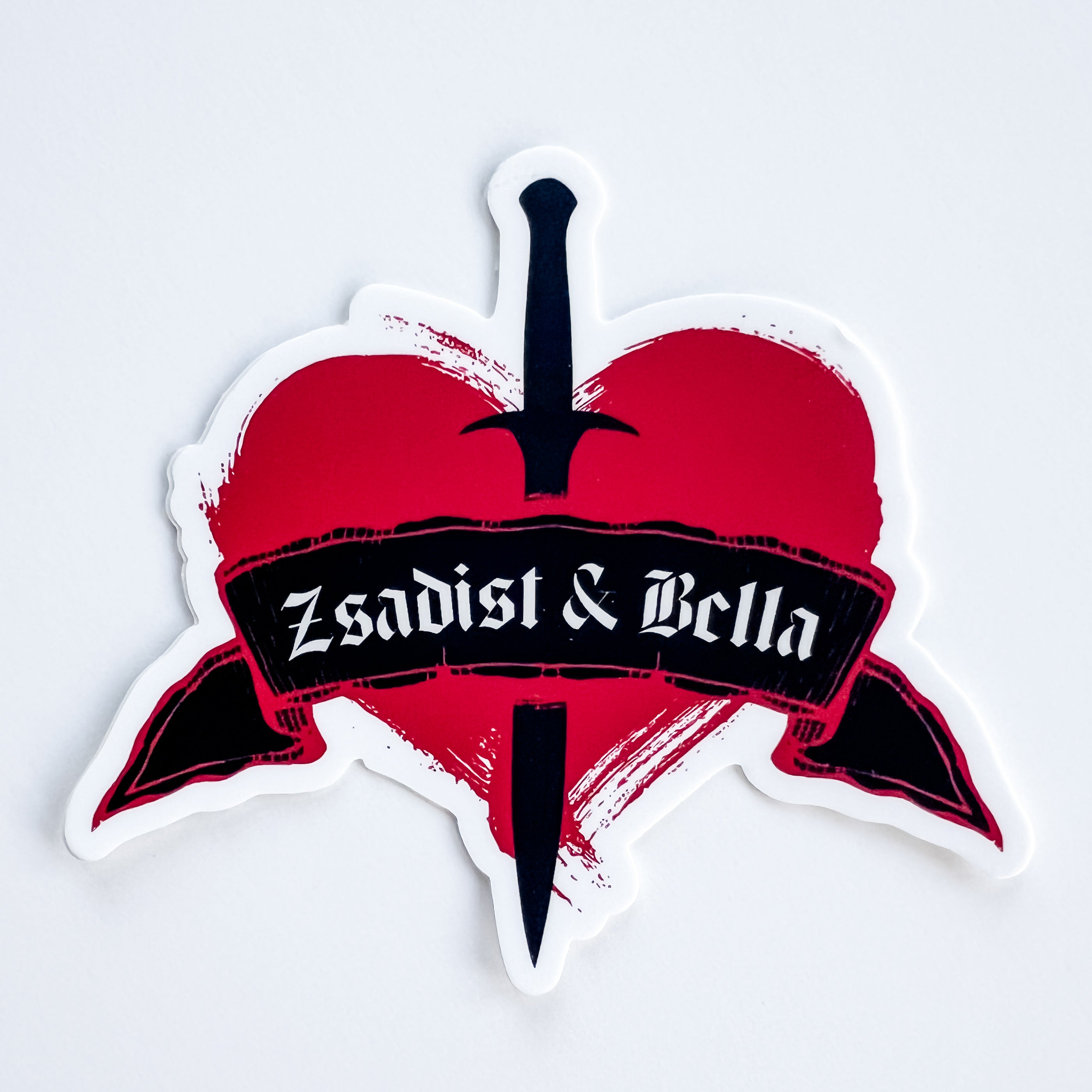Sticker with a red heart, black sword, and 'Zsadist & Bella' text on a white background