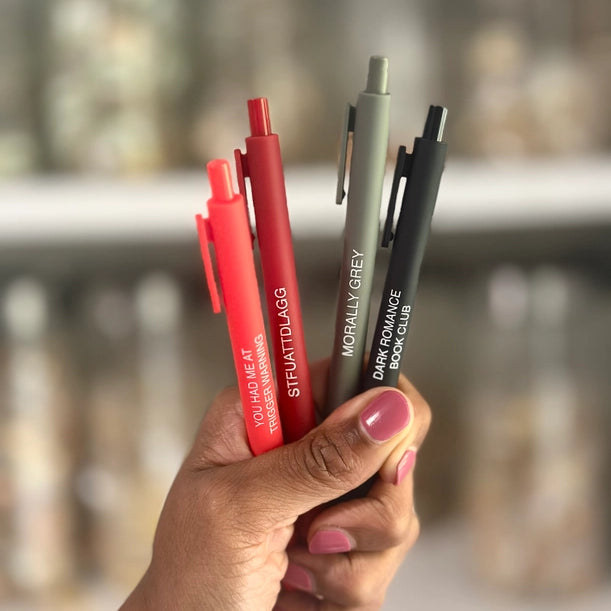 Hand holding a collection of pens with blurred background