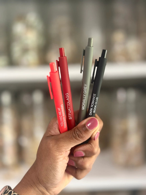 Hand holding a collection of pens with blurred background