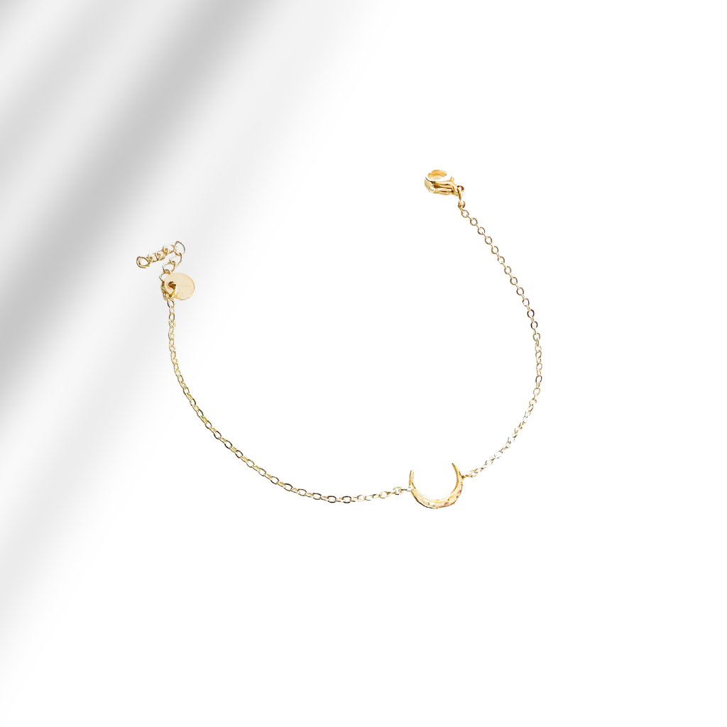 Gold bracelet with a crescent moon charm on a light gray background