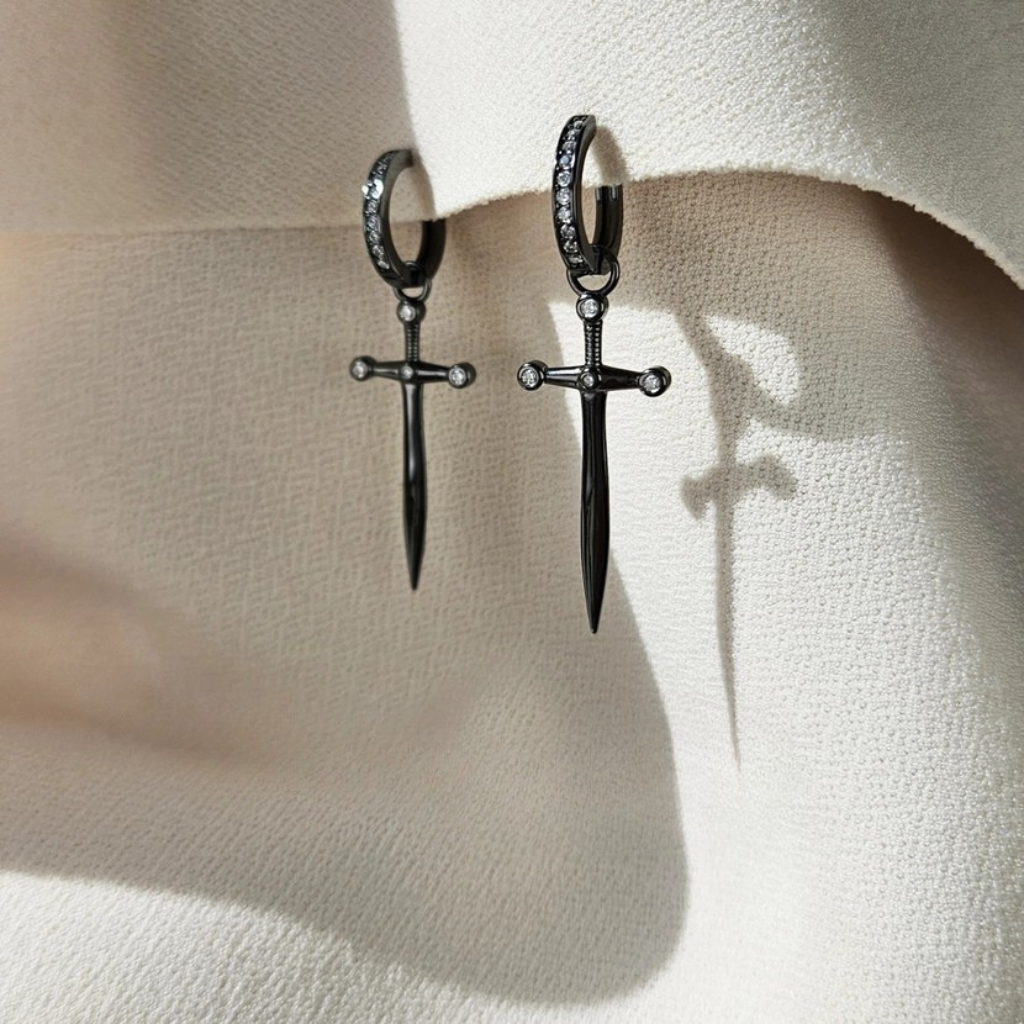 a pair of daggers on hoops over a white fabric background